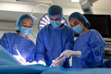 Ameliyat sırasında çeşitli cerrah takımları. Ameliyathanede İşlem Yapan Profesyonel Tıp Uzmanları. Mavi Önlüklü ve Maskeli Doktorlar. Sağlık, Tıp ve Cerrahi Ekip Çalışması.