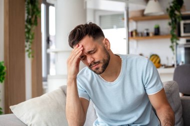 Şiddetli baş ağrısı olan bir adam alnına dokunuyor. 