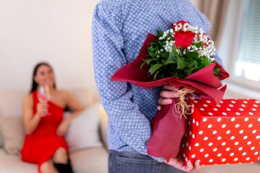 Sevgililer Günü 'nü evde kutlayan genç ve mutlu bir çift. Hoş bir iç mekanda güzel bir hediye kutusu, aşk ve ilişki konsepti olan sürpriz bir erkek..