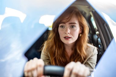 Genç kadın sürücünün yoldaki bir tehlikeye tepki vermesine şaşırdım ve şok oldum. Tehlikeli bir trafik durumunda modern bir arabanın direksiyonunda korkmuş bir ifadeye sahip kadın sürücü..