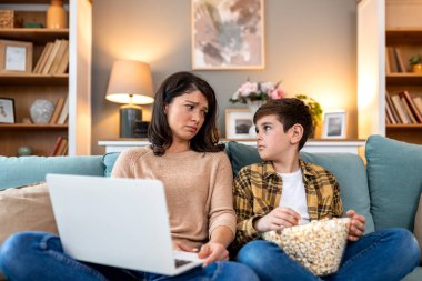 Oğlu kanepede patlamış mısır yerken, annesi dizüstü bilgisayarla uğraşmaktan yorulmuş. Uzak iş sorunları ve aile hayatı. Stresli bir kadın, evde çoklu görev yaparken çocuğa bakıyor. Ebeveynlik kariyer mücadelesine karşı..