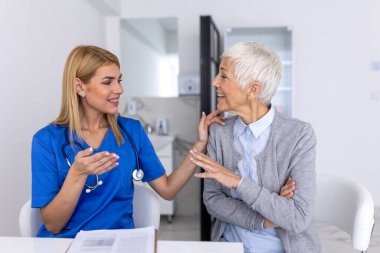 Klinik ziyareti, şefkat ve tıbbi bakıma güven sürecinde yaşlı kadınlara destek veren, el ele tutuşarak kıdemli hastayı rahatlatan profesyonel kadın doktor, sağlık hizmetleri uygulayıcısı.