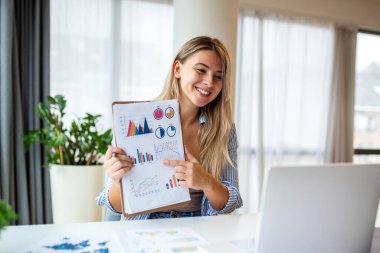 Videoda finansal tabloları gösteren gülümseyen bir kadın. Profesyonel iş adamı çevrimiçi toplantı sırasında verileri laptop ekranına açıklıyor. Uzaktan çalışma ve dijital sunum. Serbest danışman..