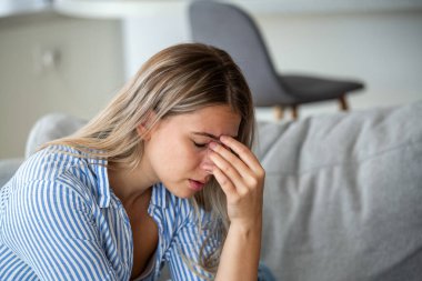 Sinüs ağrısı ve baş ağrısı. Burun basıncına ya da migrene dokunan bir kadın. Sağlık ve tıp konsepti. Kanepede oturan çekici kız alerji ya da soğuk algınlığından muzdarip..