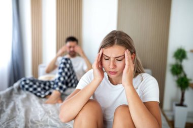 Yatak odasında bir çift sorun ve ilişki krizi var. Stres ve Akıl Sağlığı konsepti. Mutsuz kadın yatakta oturmuş hayal kırıklığına uğramış hissederken arka plandaki adam bulanık. Evlilik sorunları olan insanlar..