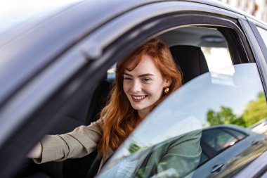 Gülümseyen Kızıl Saçlı Kadın Şehirde Araba Kullanıyor, Modern Araç Direksiyonu, Araba Sahipliği ve Otomotiv Sigortası Arkasında Mutlu Kafkasyalı Kadın