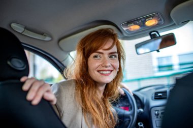 Kadın sürücü, şehir ortamında bir arabayı ters çevirirken geriye bakıyor. Araç güvenliği, park yardımı, sürücü eğitimi ve otomotiv sigortası koruması kavramı.