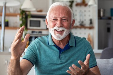 Video Çağrısında Mutlu Kıdemli Adam Hareketleri, Gülümseyen Olgun Erkek Kamerayla Konuşuyor, Duygusal Büyükbaba Sohbeti Online. Beyaz sakallı neşeli yaşlı insan evde iletişim kuruyor..
