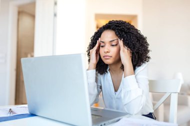 İş yerinde başım ağrıyor. Migren ve stres, sağlık sorunu olan siyah kadın, tıp konsepti. Afrika kökenli Amerikalı bir kadın ofis bilgisayarında çalışırken el ele tutuşup masa başında oturuyor..