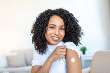 Gülümseyen Siyah Kadın Aşıdan sonra Kolunda Bandaj Gösteriyor. İğne ya da aşıdan sonra mutlu kadın hastalar. Evde Sağlık, Tıp ve Hastalık Önleme Konsepti.