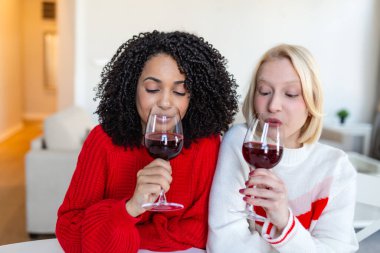 Evde Gözlüklü Kırmızı Şarap Kokan Çeşitli Genç Kadınlar. Kadın Arkadaşlar Oturma Odasında Şarap Tadına Bakıyorlar. Hafta sonu tatili ya da Şarap Tadına Bakarken Aroma ve Şarap Zevkini Çıkaran İki Kadın.