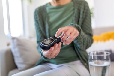 Şeker seviyesini ölçmek için kan şekeri ölçer kullanan yaşlı bir kadının ellerini kapat. Diyabet hastası. Dijital glukometreyle kan tahlili yapıyor. Sağlık ve Diyabet Kontrol Konsepti.