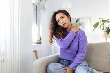 Omzum ağrıyor. Üst kol ağrısı, kas problemi, sağlık sigortası ve ilaç konsepti olan insanlar. Çekici bir kadın yatakta oturuyor ve başka bir elle ağrılı bir omuz tutuyor..