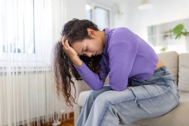 Baş ağrısı ve migren. Akıl sağlığı, stres sorunu olan insanlar, sağlık sigortası ve tıp konsepti. Depresyondaki Asyalı kadın kanepede oturuyor ve elleriyle acı veren kafasını tutuyor. Yorgun kadın..