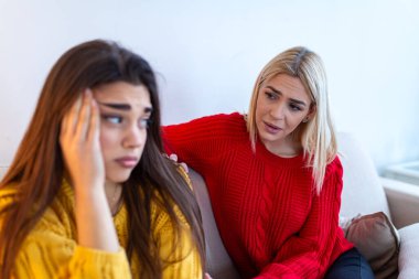 Destek ve rahatlık kavramı. Üzgün arkadaşını baş ağrısı ya da hayat sorunlarıyla rahatlatan nazik bir kadın. İki bayan arkadaş evdeki kanepede konuşuyor. Empati, akıl sağlığı ve arkadaşlık. Depresyon.