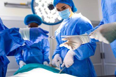 Cerrahlar steril eldivenleriyle hastalara cerrahi aletler uzatıyor. Doktorlar ameliyathanede tıbbi prosedür uyguluyor. Sağlık ve tıp konsepti. Profesyonel cerrahi..