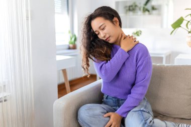 Evde sırt ağrısı ve omuz ağrısı çeken Asyalı bir kadın. Bel Ağrısı. Kadın sırt ağrısı hisseder masaj yapar kaslar ağrır, üzgün kadın bel ağrısı çeker.