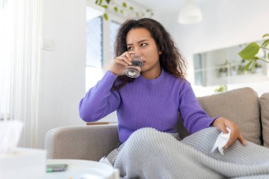 Asian ill sick woman taking painkiller medicine to relieve stomachache pain sit on bed in the morning. Sick woman lying in bed with high fever. Cold flu and migraine.