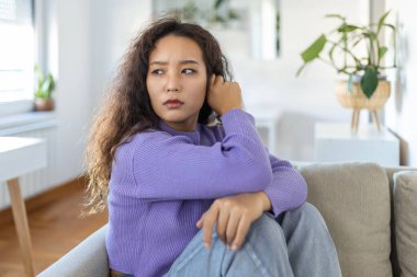 İşle ya da ilişkilerle ilgili sorunları olan üzgün bir kadın, koltukta oturuyor, yüzü örtülü, umutsuzluk ve endişe hissediyor, yalnızlık çekiyor, psikolojik sorunlar yaşıyor.