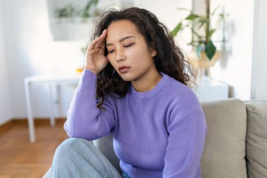 Sinus ache causing very paintful headache. Unhealthy Asian woman in pain. Sharp strong sore. Sinus pain, sinus pressure, sinusitis. Sad woman holding her head because sinus pain