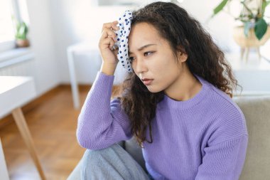 Close-up shot of a Asian woman suffering from a headache cooling her head with a ice pack