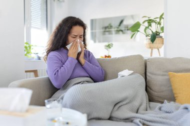 Sick desperate woman has flu. Rhinitis, cold, sickness, allergy concept. Asian sick woman has runnning nose, rubs nose with handkerchief. Sneezing female. Brunette sneezing in a tissue