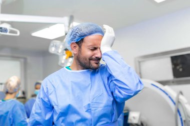 Başarısızlık! Cerrah ameliyat yatağının üzerinde eğiliyor. Başarısız bir ameliyattan sonra kendini üzgün ve yorgun hissediyor..