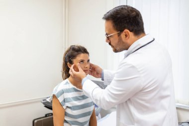 Yetişkin bir kadın göz doktorunun muayenehanesini ziyaret ediyor. Klinikteki genç bayanın gözlerini muayene eden doktor..