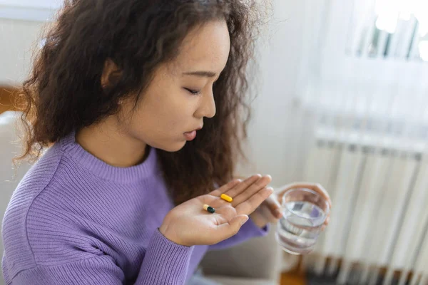 Asian ill sick woman taking painkiller medicine to relieve stomachache pain sit on bed in the morning. Sick woman lying in bed with high fever. Cold flu and migraine.