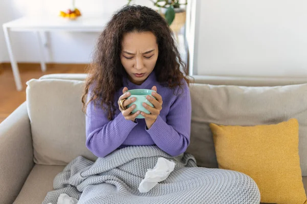 Closeup view of young Asian woman with cup of hot drink at home, covered with blanket. People, drinks and leisure concept - young woman with cup of tea or coffee at home