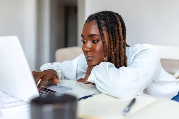 Uzak iş, teknoloji ve insan konsepti - Covid-19 sağlık krizi sırasında merkez büroda çalışan dizüstü bilgisayarı ve kağıtları olan genç Afrikalı iş kadını.