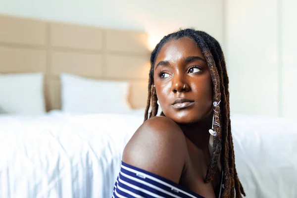 Evde gülümseyen güzel bir kadının portresi. Sıradan giyinmiş Afrikalı bir kadın fotokopi makinesiyle kameraya bakıyor. Neşeli melez kız evde dinleniyor.