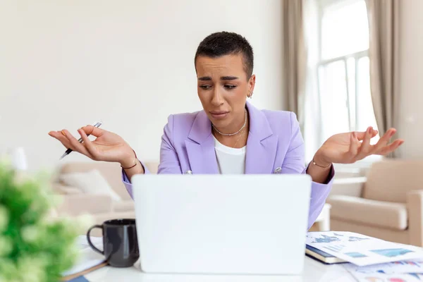 Hüsrana uğramış genç Afrikalı Amerikalı iş kadını ofiste masa başında dizüstü bilgisayarla çalışıyor..