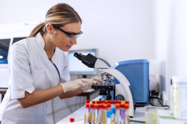 Genç bilim adamı bir laboratuvar mikroskop aramak. Biraz araştırma yaparak genç bilim adamı.