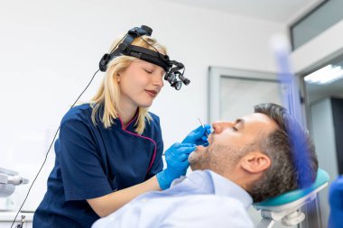 Modern klinikte erkekler için tedavi yapan iki kişinin toplu portresi. Kapalı alanda dişçilik için tıbbi konsept fotoğrafçılık. Diş hekimliği, klinikte hastalarla çalışan bir doktor..