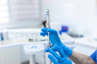 Anestezi şırıngasını bir diş hekiminin eline ver. Anestezi doktoru diş ameliyatından önce elinde anestezi şırıngası tutuyor. Lastik eldiven verin.