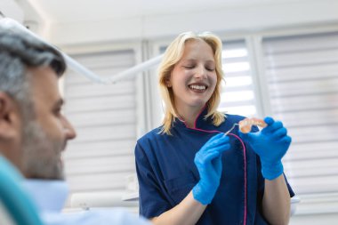 Hastaya diş macunu kalıbı gösteren bir diş hekimi. Diş hekimi diş sağlığı kliniğinde çene modeli gösteriyor, diş bakımı konsepti. Diş sağlığı konsepti.