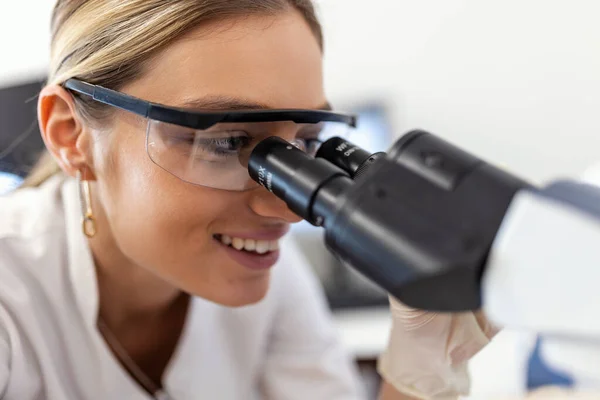 Genç bilim adamı bir laboratuvar mikroskop aramak. Biraz araştırma yaparak genç bilim adamı.