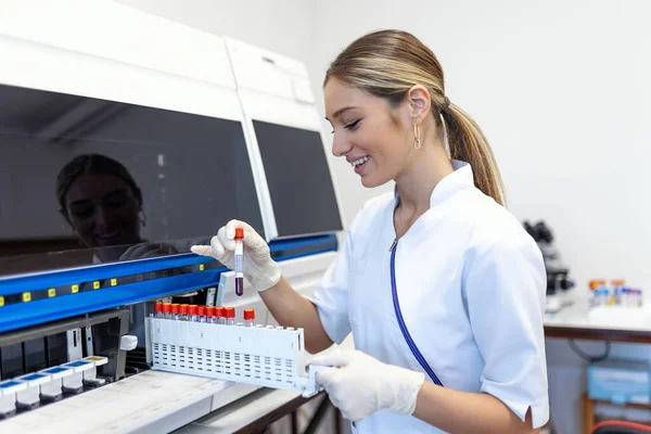 Lab tech loading samples into a chemistry analyzer. female lab tech loading specimen for coagulation test analysis