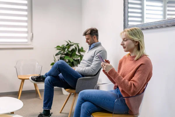 İnsanlar, erkek ve kadın bir sırada oturup, hastanede doktor randevusu bekliyorlar. Bekleme odası konsepti.