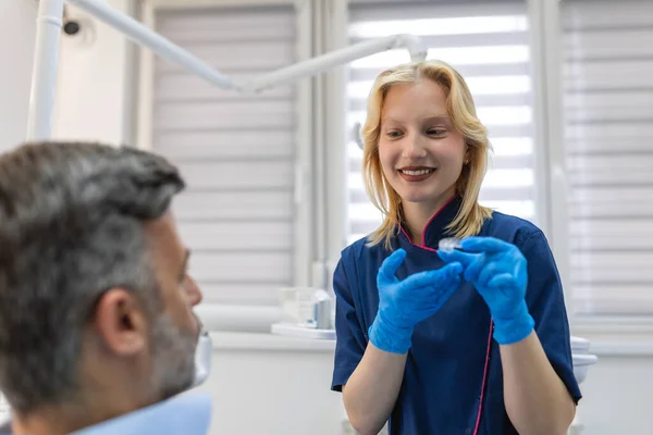 Dişçi görünmez diş tellerinin hizalandığını gösteriyor. Bir ortodontik kliniğinde diş muayenesi. Diş hekiminde ortodontik düzelticiler. Diş tedavisi kavramı.