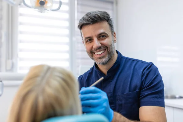 Tıp merkezindeki dişçi koltuğunda oturan tatmin olmuş genç bir kadın resmi.