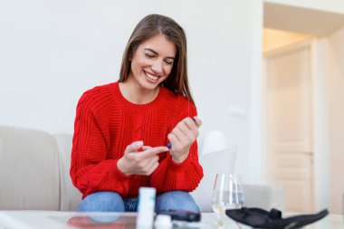 Kadın parmak üzerinde mızrak kullanıyor. Oturma odasında kan şekeri testi yapan bir kadın..