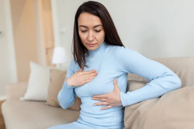 Asyalı kadın göğsündeki yumruları göğüs kanseri belirtileri için kontrol ediyor. Kadın göğüs ağrısından muzdarip. BSE ya da Göğüs Kendi Muayenesi. Göğüs kanserini kontrol etme kılavuzu.