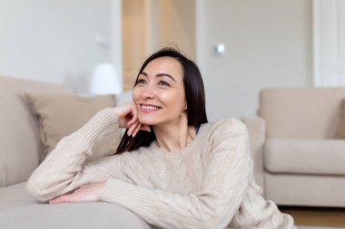 Kameraya bakan orta yaşlı, gülümseyen Asyalı kadının portresi. Evde gülümseyen güzel bir kadın..