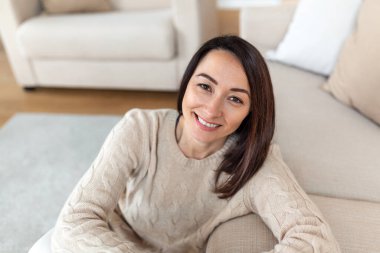 Kameraya bakan orta yaşlı, gülümseyen Asyalı kadının portresi. Evde gülümseyen güzel bir kadın..