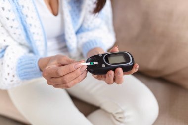 Olgun Kadın yüksek kan şekeri için test. Kan şekerini ölçmek için kadın tutma cihazı. Kan şekeri testi yapan kadın. Kadın evde glucometer ve test şerit tarafından kan şekeri seviyesini kontrol