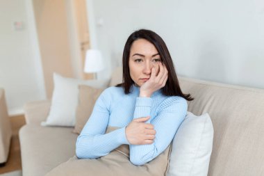 Hüsrana uğramış Asyalı kadın kanepede oturuyor, yastığa sarılıyor, pencereye bakıyor. Düşüncelere dalmış mutsuz bir kadın yanlış karardan pişmanlık duyuyor, oturma odasında yalnız zaman geçiriyor..