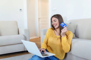 Güzel bir kadının kredi kartıyla alışveriş yaptığını gösteren bir fotoğraf. Kredi kartı tutan ve laptop kullanan bir kadın. Çevrimiçi alışveriş kavramı