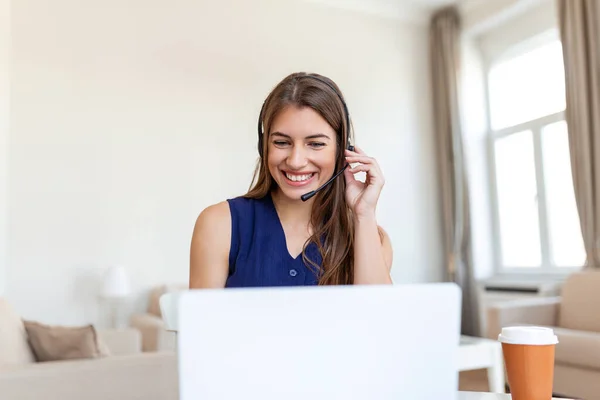 Happy young woman in headphones speaking looking at laptop making notes, business woman talking by video conference call, Conference by webcam, online training, e-coaching concept